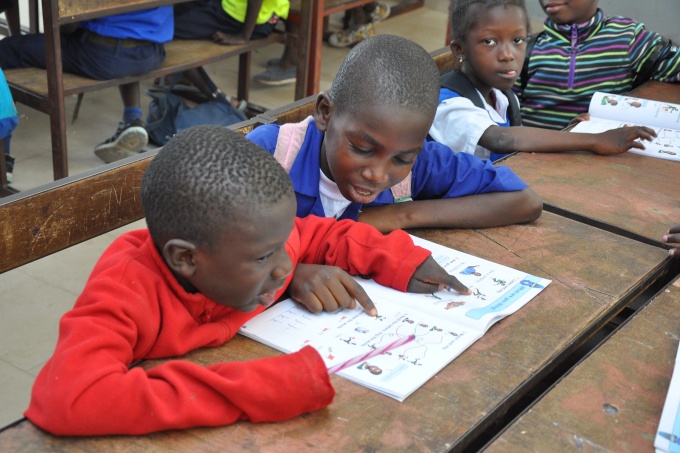 Students sharing a textbook in class. The Gambia, February 2019. Credit: GPE/Jim Cham